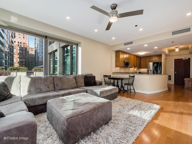 living room with light hardwood / wood-style floors and ceiling fan