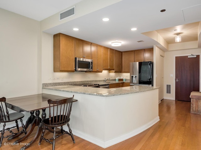 kitchen featuring kitchen peninsula, light hardwood / wood-style flooring, stainless steel appliances, and sink