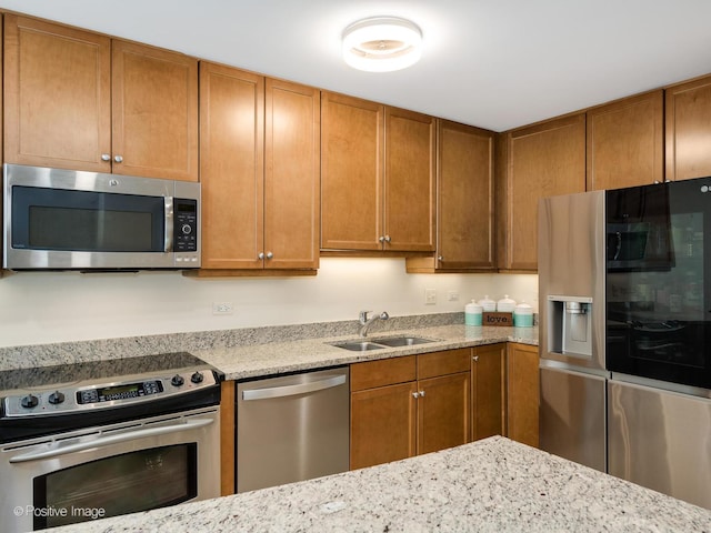 kitchen with light stone countertops, sink, and stainless steel appliances