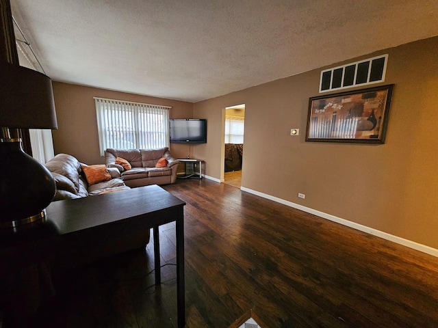 living room featuring dark wood-type flooring and a textured ceiling