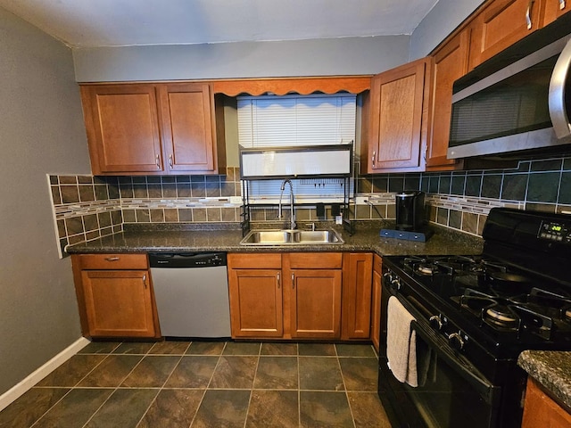 kitchen with appliances with stainless steel finishes, backsplash, dark stone counters, and sink