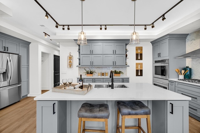 kitchen featuring stainless steel refrigerator with ice dispenser, a sink, a kitchen island with sink, and pendant lighting