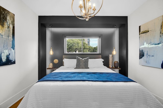 bedroom featuring a notable chandelier, baseboards, and wood finished floors