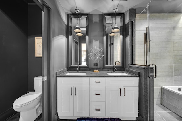 bathroom featuring a garden tub, double vanity, toilet, a sink, and a shower stall