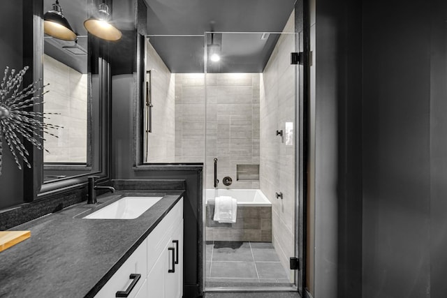 bathroom with tiled tub, vanity, and tile patterned floors