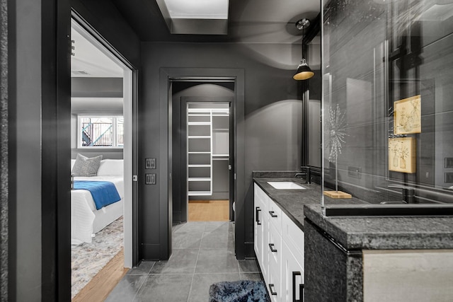 bathroom featuring double vanity, backsplash, a spacious closet, connected bathroom, and a sink