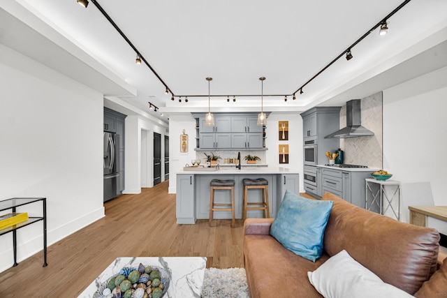 living room with baseboards, rail lighting, and light wood-style floors