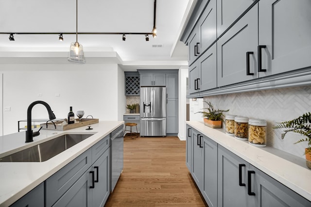 kitchen featuring visible vents, appliances with stainless steel finishes, hanging light fixtures, gray cabinetry, and a sink