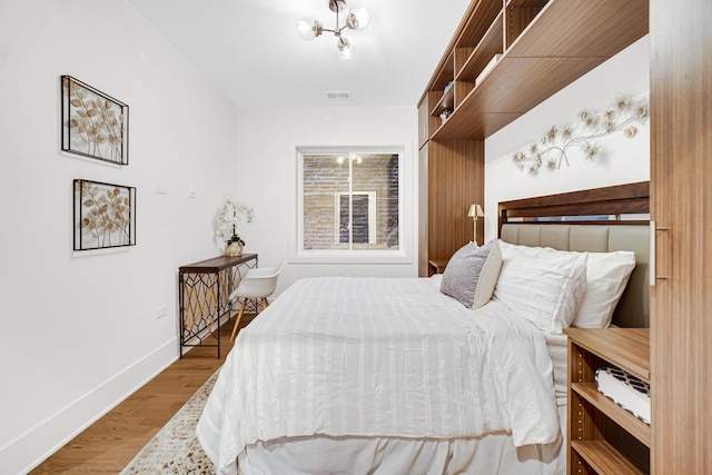 bedroom with visible vents, baseboards, and wood finished floors