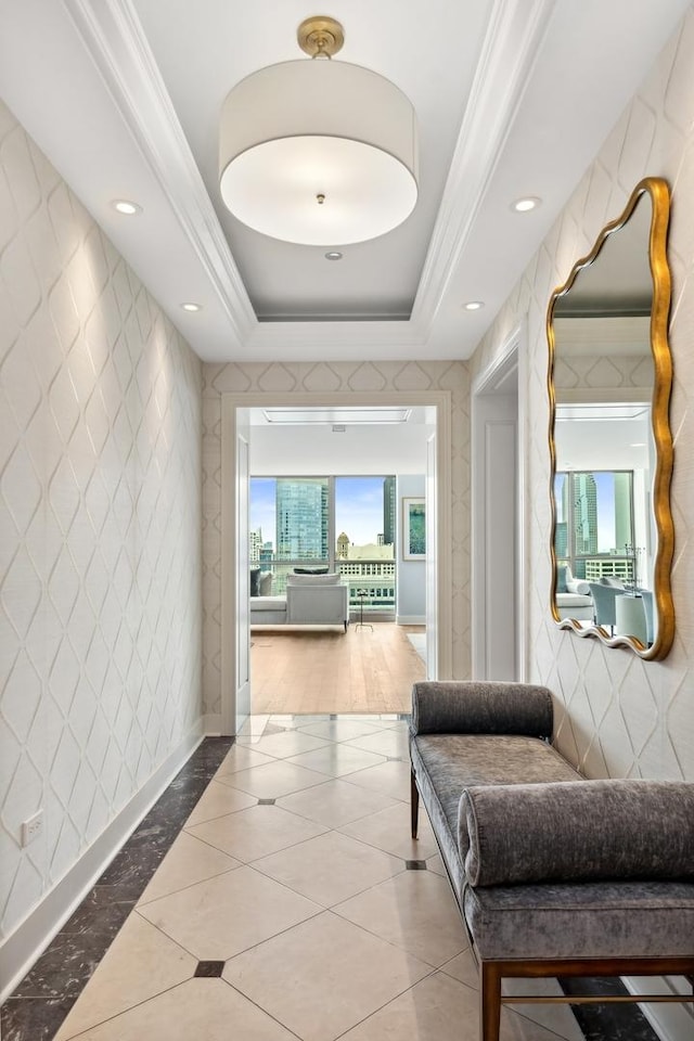 corridor with ornamental molding and a tray ceiling