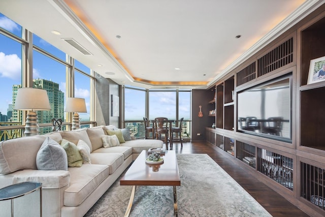 living room with dark hardwood / wood-style flooring, a tray ceiling, and expansive windows