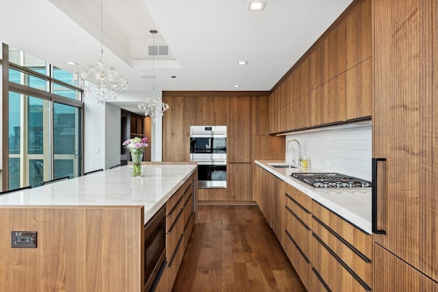 kitchen featuring tasteful backsplash, dark hardwood / wood-style floors, a notable chandelier, a spacious island, and appliances with stainless steel finishes