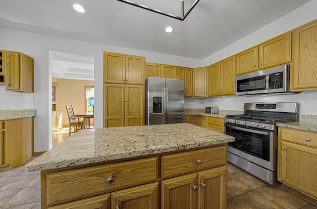 kitchen featuring decorative backsplash, light stone countertops, a kitchen island, and stainless steel appliances