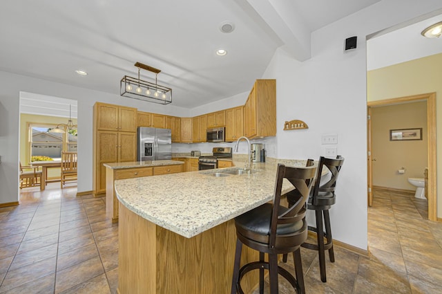 kitchen with kitchen peninsula, appliances with stainless steel finishes, light stone countertops, sink, and beamed ceiling