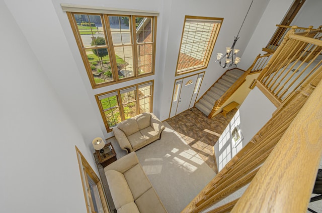 living room with carpet flooring, a towering ceiling, and an inviting chandelier