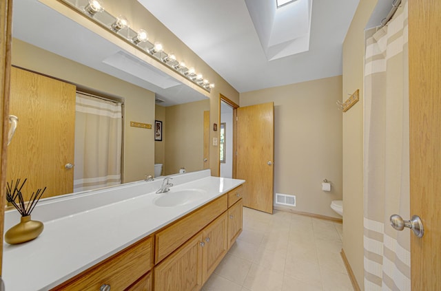 bathroom featuring vanity, toilet, and a skylight