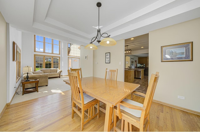 dining space featuring a raised ceiling and light wood-type flooring