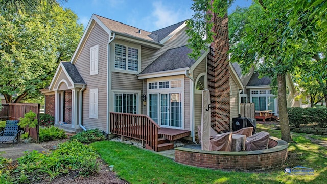 back of property featuring a lawn and a deck