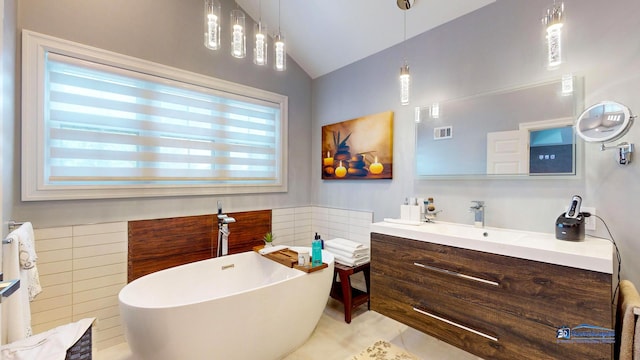 bathroom featuring a bathing tub, vanity, lofted ceiling, and tile patterned floors