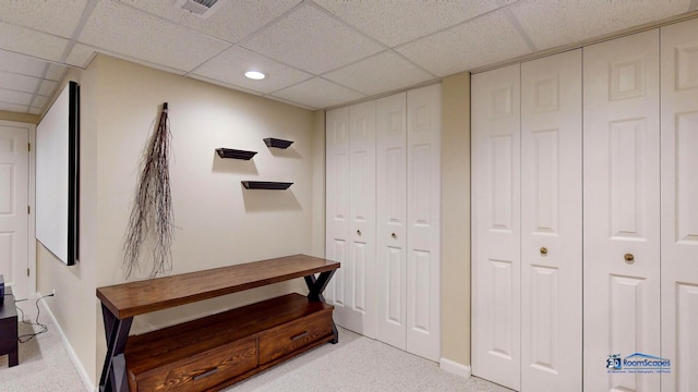 carpeted bedroom featuring multiple closets and a paneled ceiling