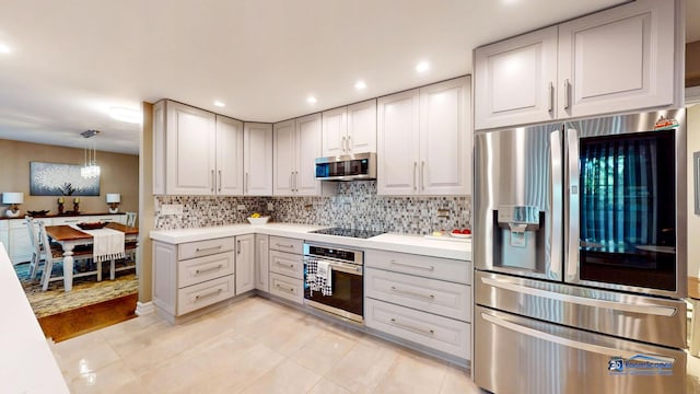 kitchen featuring light tile patterned floors, backsplash, stainless steel appliances, and decorative light fixtures