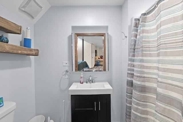 bathroom featuring vanity, lofted ceiling, and toilet