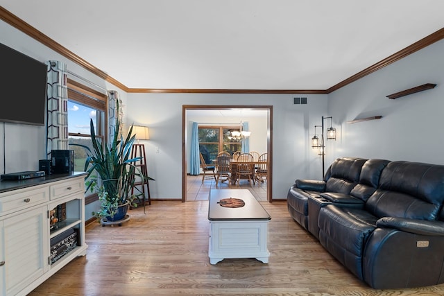 living room with crown molding, light hardwood / wood-style flooring, and a chandelier