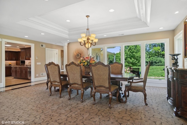 dining room featuring ornamental molding, decorative columns, a raised ceiling, and a notable chandelier