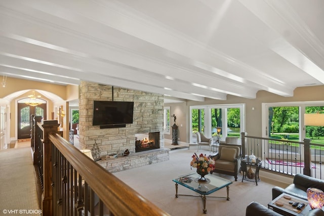 living room with beamed ceiling, light colored carpet, a fireplace, and an inviting chandelier