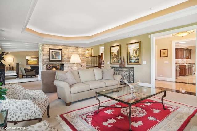 living room with a tray ceiling and a stone fireplace