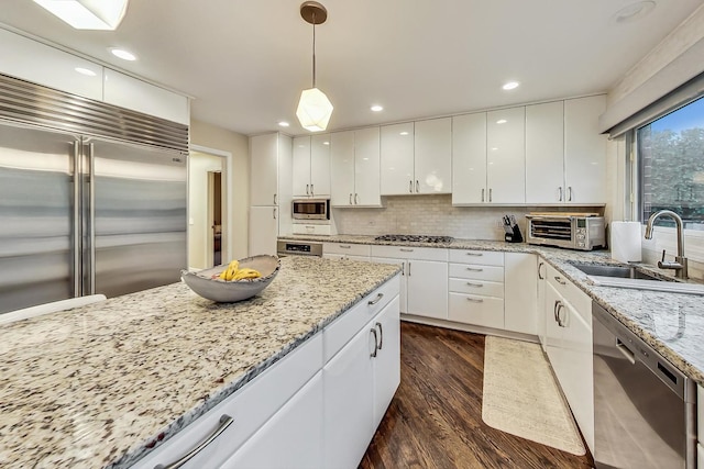 kitchen with white cabinets, sink, dark hardwood / wood-style floors, appliances with stainless steel finishes, and decorative light fixtures