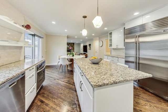 kitchen with a center island, hanging light fixtures, stainless steel appliances, decorative backsplash, and white cabinets