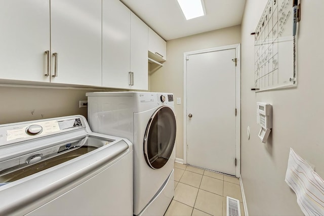 clothes washing area featuring light tile patterned flooring, cabinets, and separate washer and dryer