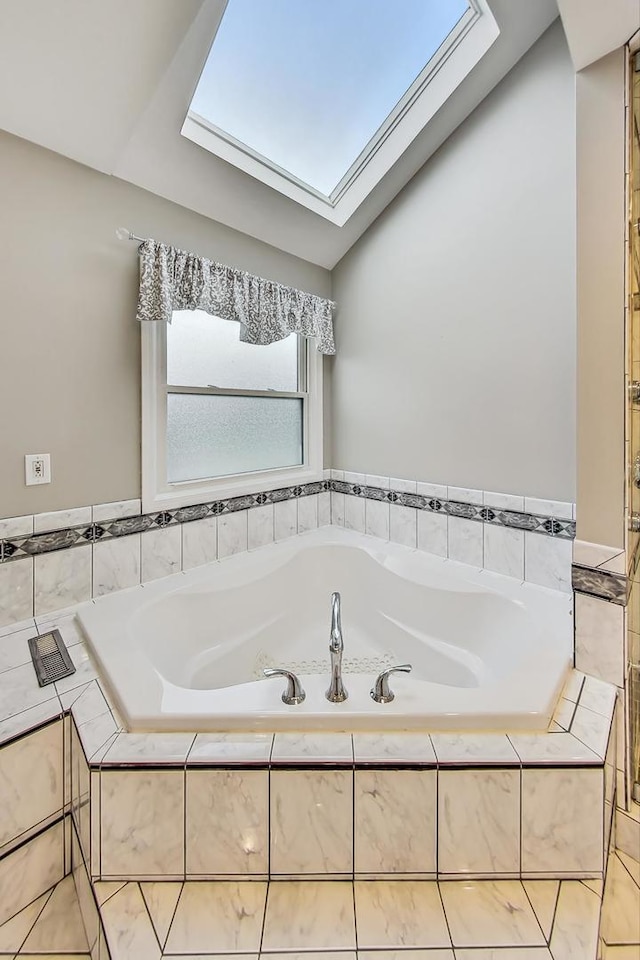 bathroom featuring a relaxing tiled tub and vaulted ceiling with skylight