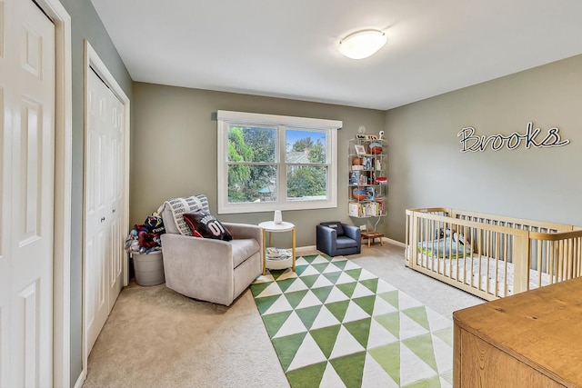 bedroom with a closet, light colored carpet, and a nursery area