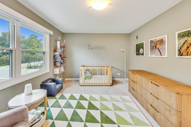 bedroom with light colored carpet and a nursery area