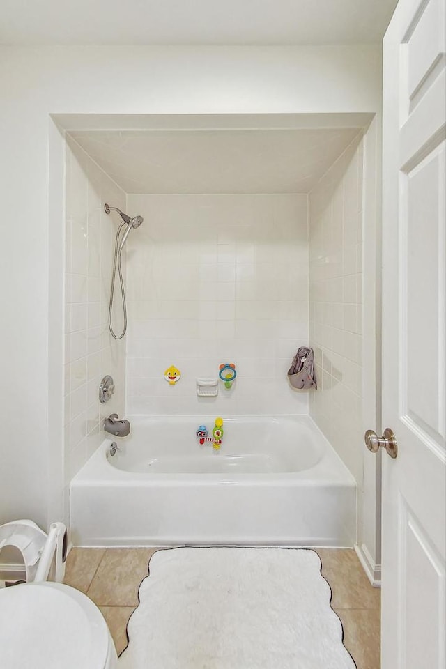 bathroom with tile patterned flooring, tiled shower / bath combo, and toilet