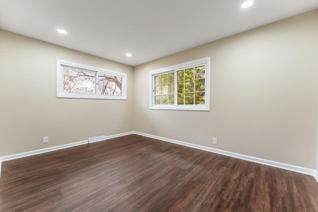 spare room with a wealth of natural light and dark hardwood / wood-style flooring