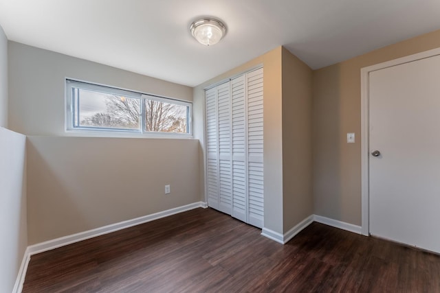 unfurnished bedroom with a closet and dark hardwood / wood-style floors