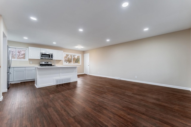 kitchen with white cabinetry, dark wood-type flooring, an island with sink, and stainless steel appliances