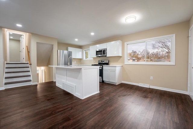 kitchen featuring white cabinets, appliances with stainless steel finishes, dark hardwood / wood-style floors, and a kitchen island with sink