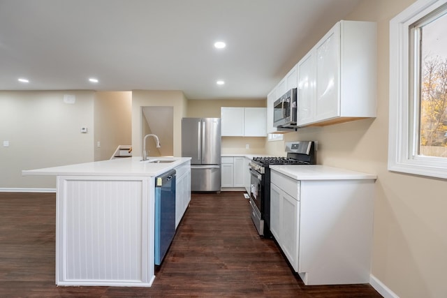 kitchen featuring appliances with stainless steel finishes, dark hardwood / wood-style flooring, a kitchen island with sink, sink, and white cabinetry