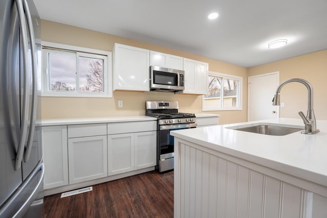 kitchen with white cabinetry, sink, stainless steel appliances, and dark hardwood / wood-style floors