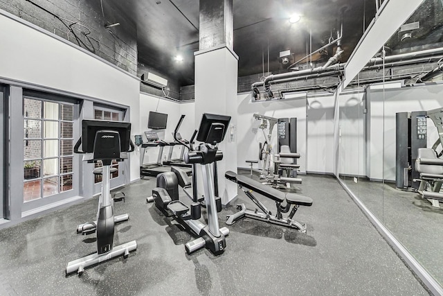 gym featuring a high ceiling and a wall mounted air conditioner