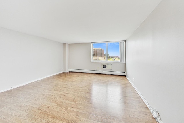 empty room with light wood-type flooring and a baseboard heating unit