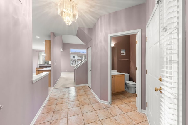 hall with light tile patterned floors and an inviting chandelier