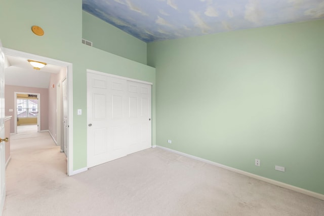 unfurnished bedroom with vaulted ceiling, light carpet, and a closet