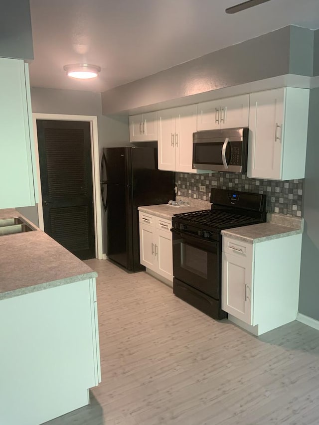 kitchen featuring white cabinets, decorative backsplash, light hardwood / wood-style floors, and black appliances