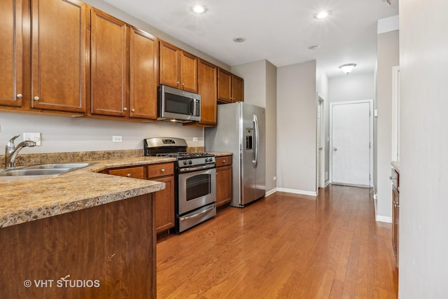 kitchen featuring appliances with stainless steel finishes, light hardwood / wood-style flooring, and sink