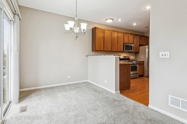 kitchen featuring hanging light fixtures, light carpet, an inviting chandelier, and stainless steel appliances